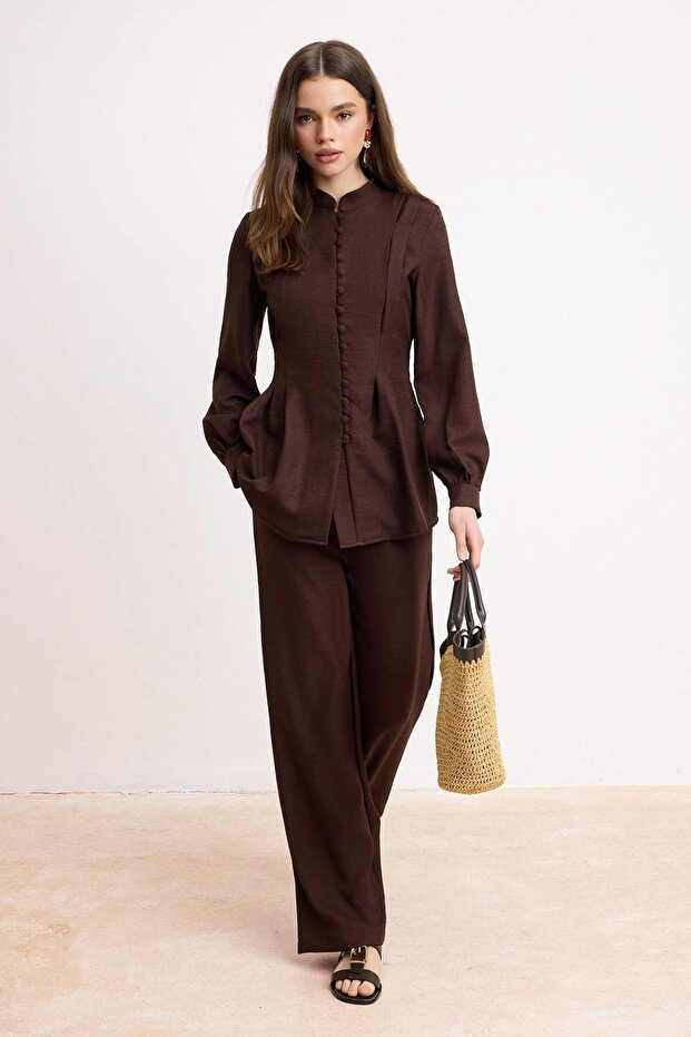 محتشم بني بمظهر الكتان بتفاصيل أزرار بلوزة وبنطال طقم علوي وسفلي طقم